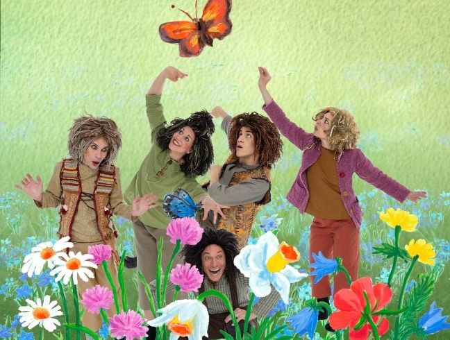 Viisi satuhahmoiksi pukeutunutta henkilöä piirretyllä kukkakedolla.