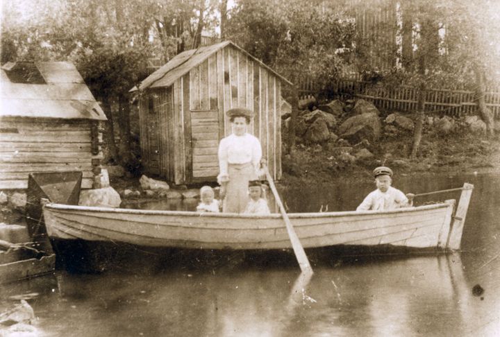 Mor och tre barn i rodbåt vid vattenbryn i Brändö, foto: SLS, Vasa
