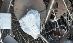Lapsen nyrkin kokoinen kimpale säteilevää ainetta romumetallin seassa.