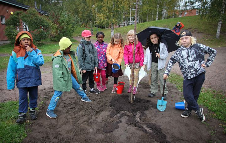 Maunulan iltapäiväkerholaiset kastelevat tämän vuoden lasten puuta istutuksen yhteydessä. Kuvaaja: Sari Knuuti