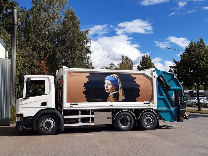 Jirka Väätäisen kierrätyskartongista tehty taideteos Tyttö ja kartonkikorvakoru piristää joidenkin HSY:n jäteautojen kylkiä.