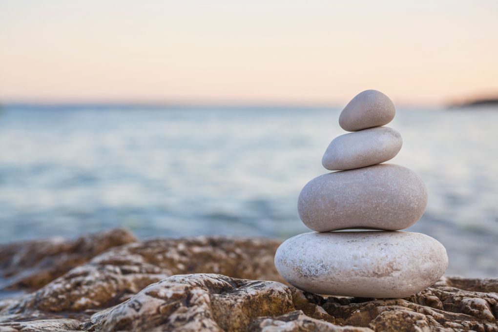 12911075-pile-of-stones-on-tranquil-beach-at-sunset.jpg