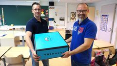 Erno Paanen, vas. luovuttaa Voimala-paketin nurmolaisen Valkiavuoren koulun rehtori Kari Kunnarille