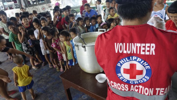 Filippiinien Punaisen Ristin vapaaehtoiset jakamassa ruokaa evakuointikeskuksessa. Kuva: Filippiinien Punainen Risti
