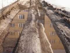Lumisella kadulla ajourien vesi heijastaa kerrostalon julkaisivua. Kuva: Stanislaw Mikulski, AdobeStock.