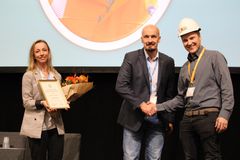 Joensuulainen Olli Ryhänen (oik.) on Vuoden Nuori Rakennusmestari 2022. Kunniakirjaa ojentaa Rakennusmestarit ja -insinöörit AMK RKL ry:n toimitusjohtaja Maria-Elena Ehrnrooth, puheenjohtaja Jukka Lintunen kättelee. Kuva: RKL ry