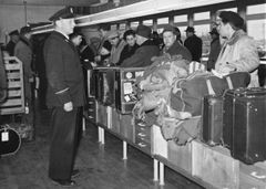 Matkustajia ja tullitarkastaja Iivari Saarinen Helsingin lentoaseman tullissa keväällä 1954.  Kuva: Relander / Suomen Ilmailumuseo.