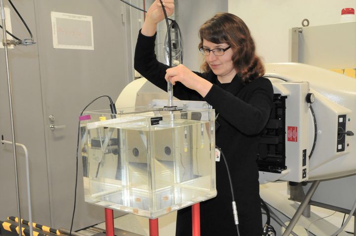 Säteilyturvakeskuksen erikoistutkija Reetta Nylund asentaa sädehoidon mittauksiin käytettävää säteilymittaria kalibrointia varten.