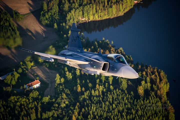 Ruotsin Ilmavoimien Gripen C monitoimihävittäjä suomalaisen maalaismaiseman yllä. Kuva Rich Cooper / COAP