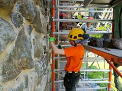 Liisa Mendelin och Pauliina Koivunen iståndsätter ruinkyrkans murar under sommaren. Skadade stenar och tegel avlägsnas från murarna innan man kan mura på nytt. Bild: Ilari Rautiainen