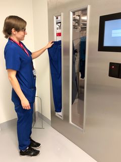 Palveluneuvoja Tuija Peltoharju ottaa työasun housuja vaateautomaatista.