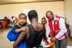 Thabile käy hakemassa Punaisen Ristin käteisavustusta Melusi-vauvan kanssa. Avunsaajia rekisteröi Samson Dlamini. Punainen Risti jakaa ruoka-apua ja ruokatukeen suunnattuja käteisavustuksia ruokapulasta pahiten kärsivillä alueilla. Ensisijaisesti autetaan kaikkein haavoittuvimmassa asemassa olevia ihmisiä, kuten vanhuksia, yksinhuoltajia ja vammaisia. Kuva: Ville Palonen