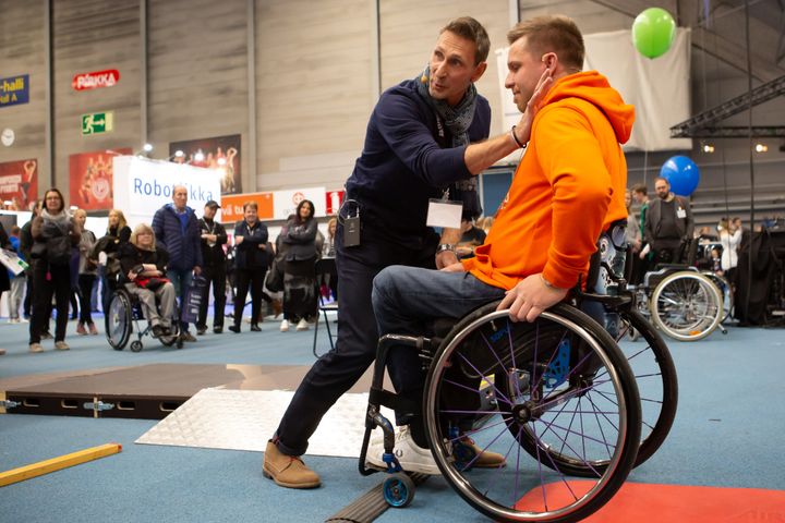 Markku Poikela opastamassa pyörätuolin käyttöä apuvälineradalla Harri Ahteen kanssa.