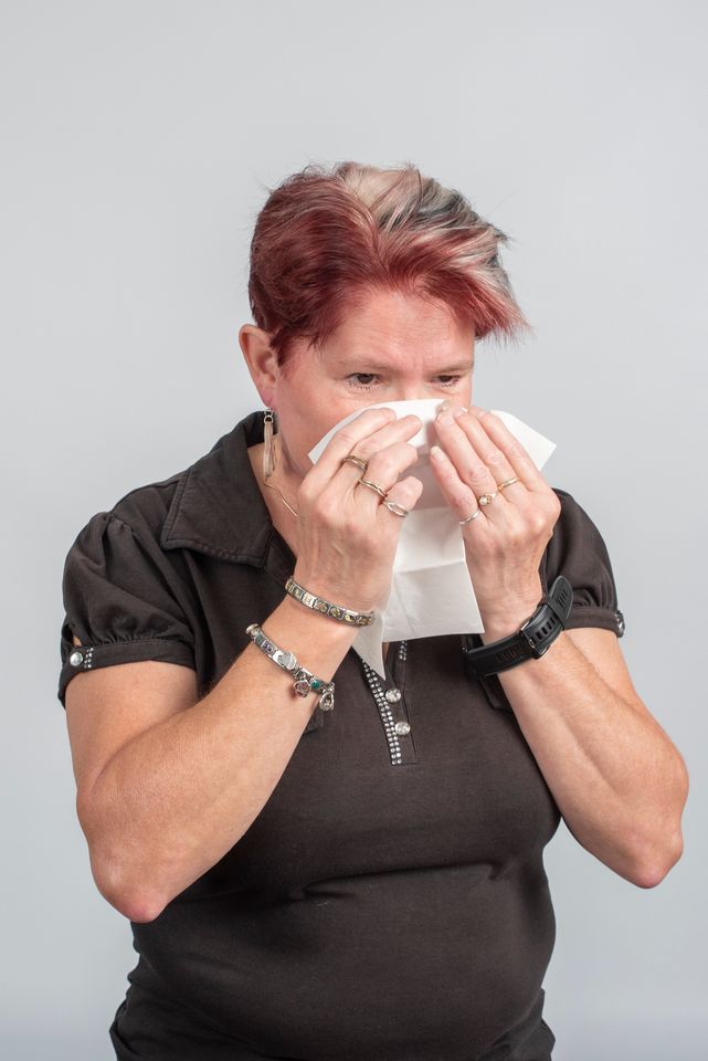 Nainen niistää nenää (pysty)
