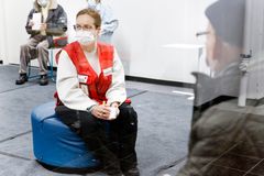 Suomen Punaisen Ristin ensiaputaitoiset vapaaehtoiset auttavat rokotettujen jälkitarkkailussa. Helena Heinonen keskustelee rokotettujen kanssa Vantaalla.
