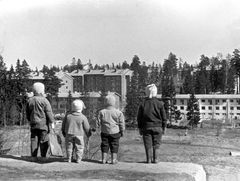 Maunulaa katsottuna hiihtomäeltä, etualalla lapsia. Hulkkonen, valokuvaaja.  
1957 - 1958. Helsingin kaupunginmuseo. CC BY 4.0.