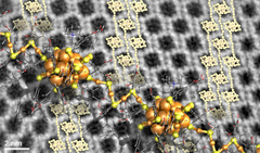 Taustalla näkyvä elektronimikroskoopin kuva kultaklustereista (tummat alueet) koostuvasta järjestyneestä kiteestä voidaan selittää tiivisti pakkautuneilla klusteririhmoilla (vaaleat pienet atomit). Etualalla suurennettu atomirakenne kahdesta kultaklusterista ja niitä yhdistävästä kulta-ligandi-ketjusta. Grafiikka: Sami Malola, Jyväskylän yliopisto