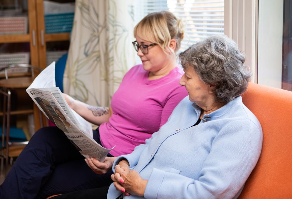 Hoitaja ja asukas lukemassa lehteä Attendo-kodissa