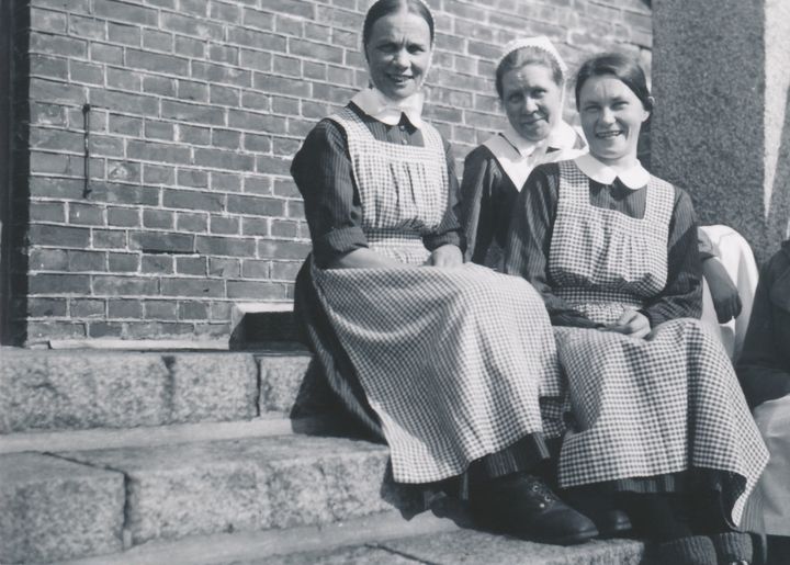 Kolme sisarta, joista kaksi diakonissaa ja yksi koesisar, istuvat diakonissalaitoksen edustalla 1930-luvulla. Diakonissalaitos oli sisäoppilaitos, jossa asuttiin ja opiskeltiin tavoitteena diakonissan vihkimys. Myös vihkimyksen jälkeen diakonissat olivat sisarkodin yhteisöä. Koulutuksen antajaksi muodostettiin Helsingin Diakonissalaitoksen sairaanhoitajakoulu 1932. Se toimi pitkään nimellä Helsingin Diakoniaopisto 1969–2016. Vuoden 2017 alusta opisto muodosti yhdessä Lahden Diakonian instituutin ja Oulun Diakoniaopiston kanssa Suomen Diakoniaopiston. Kuva: HDLA