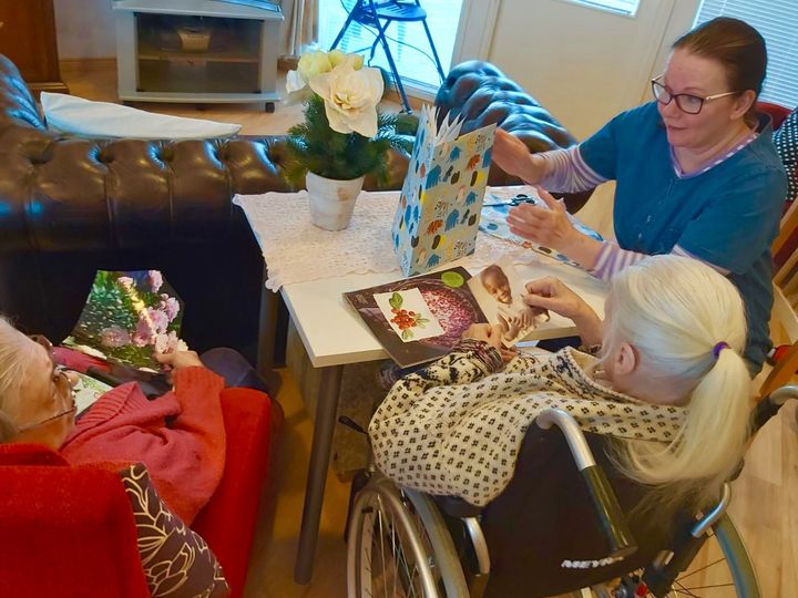 Espoolaisessa Sateenkaari-Kodissa asukkaat ja henkilökunta kokoontuvat yhteen lukemaan aikakauslehtiä ja poimivat niistä mieluisia kuvia, jotka kootaan yhteiseen leikekirjaan. Kuva: Sateenkaari-Koti.