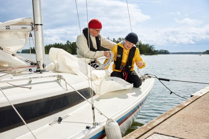 Kaksi iloista purjehtijaa istuvat purjeveneessä