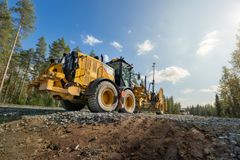 Alt-teksti: Keltainen työkone soratiellä metsäisessä ympäristössä aurinkoisena päivänä.