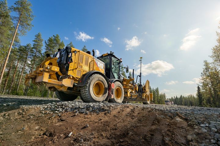 Alt-teksti: Keltainen työkone soratiellä metsäisessä ympäristössä aurinkoisena päivänä.