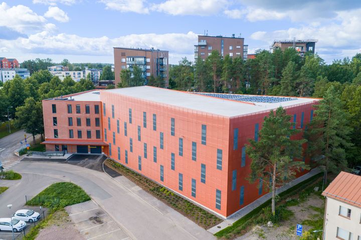 Ilmakuva oranssista pysäköintitalosta vehreällä alueella.