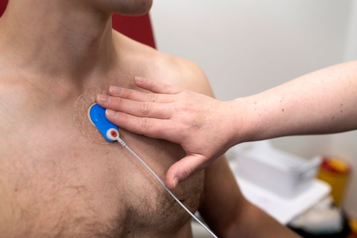 Terveydenhuollon ammattilainen kiinnittää EKG-elektrodia potilaan rintaan vastaanotolla.