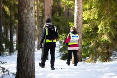 Kaksi keltaisiin liiveihin pukeutunutta Vapepan vapaaehtoista kävelemässä lumisessa metsässä.
