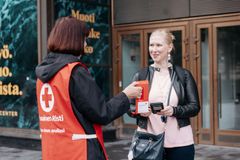 En Hungerdagsinsamlare ger en insamlingsbössa till en förbipasserande på gatan.