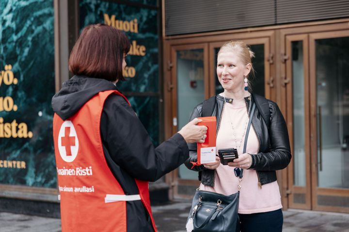 En Hungerdagsinsamlare ger en insamlingsbössa till en förbipasserande på gatan.