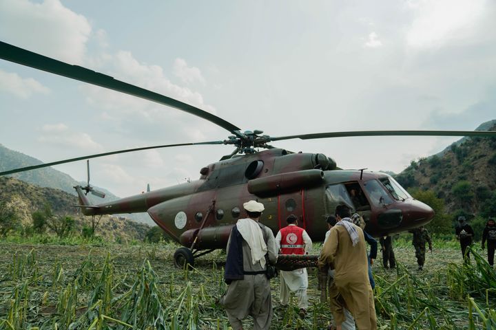 Punaisen Puolikuun vapaaehtoiset kantavat loukkaantunutta helikopteriin maaseudulla.