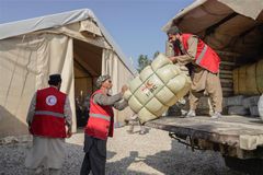 Personer i Röda Halvmånens västar lastar av biståndsmateriel från en lastbil.