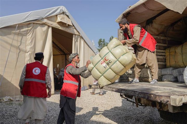 Personer i Röda Halvmånens västar lastar av biståndsmateriel från en lastbil.