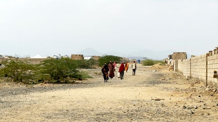 Ryhmä ihmisiä kävelee kohti kameraa Sudanissa kuivalla, kivisellä tiellä.