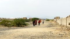 En grupp människor går mot kameran på en torr, stenig väg i Sudan.
