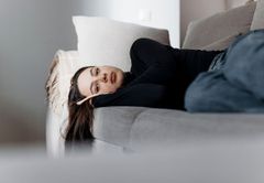 Ung person ligger tänkande på en soffa. Bild av Joonas Brandt/Finlands Röda Kors.