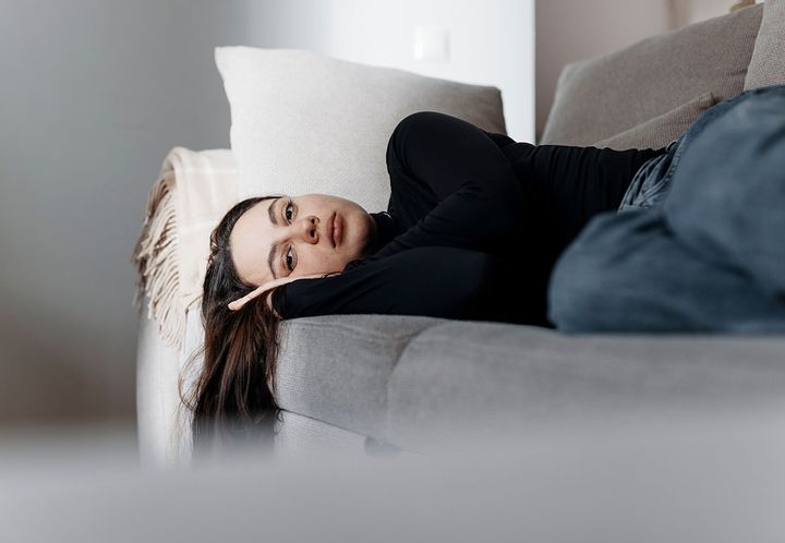 Ung person ligger tänkande på en soffa. Bild av Joonas Brandt/Finlands Röda Kors.