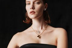 Woman in a black outfit wearing Unikko-themed jewelry from the Kalevala x Marimekko collaboration collection.