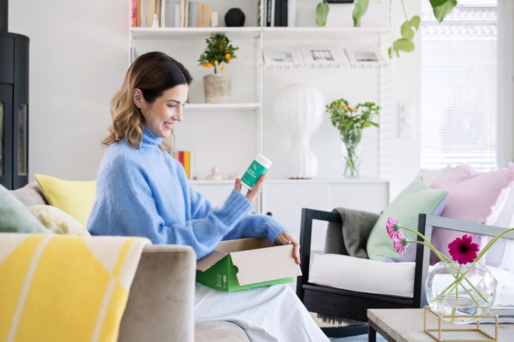 Nainen avaa verkkoapteekista tullutta pakettia kotonaan.