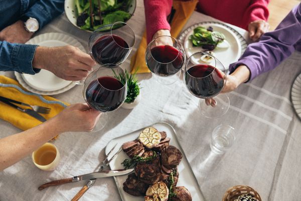 Ihmiset kilistämässä punaviinilaseja pääsiäispöydässä