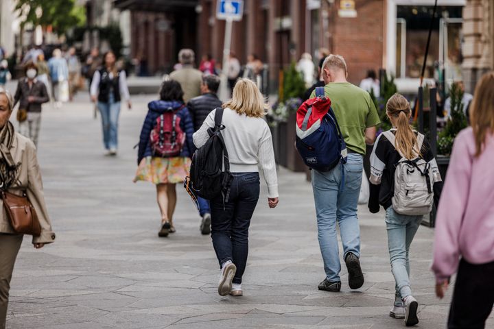 En grupp människor promenerar på en trottoar i en stadsmiljö.