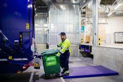 Mies kuljettaa jäteastiaa jäteautoon