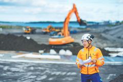 Jätehuollon asiantuntija seisoo maanrakennuskohteessa, jossa näkyy kaivinkone kaivamassa.