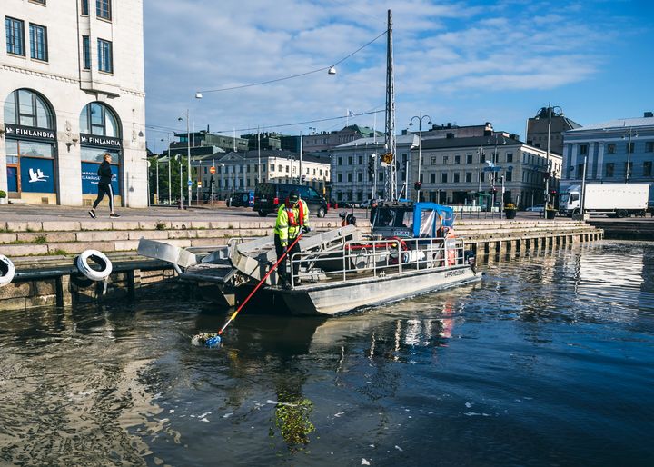 Staran työntekijä kerää roskia Lippo-aluksella Kauppatorin rannassa.