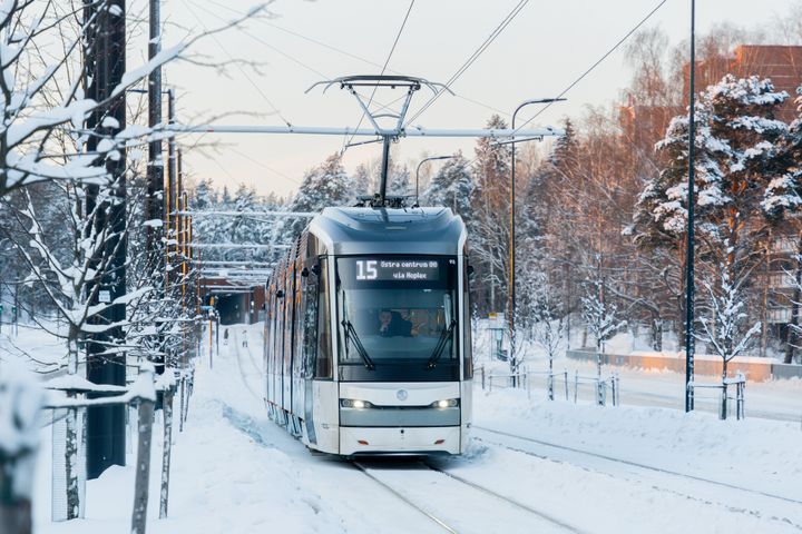 Kuvassa pikaratikka lumisessa maisemassa.
