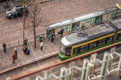 Artic-raitiovaunu ylhäältä päin kuvattuna ja matkustajia pysäkillä.