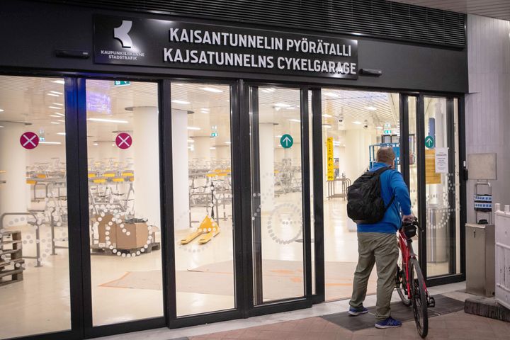 Henkilö taluttaa pyörää sisään Pyörätallin ovista.