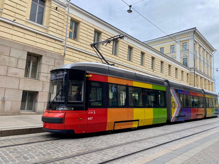 Raitiovaunu, jossa on sateenkaaren väreissä olevat teippaukset, pysäköitynä kadulle.